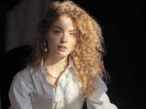 fashionable young lady in trendy outfit looking at camera against black background