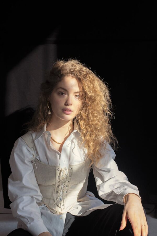 fashionable young lady in trendy outfit looking at camera against black background